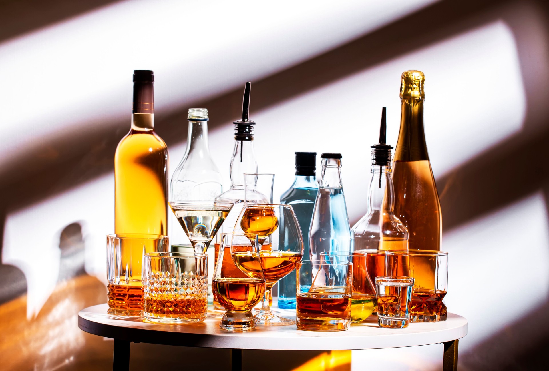 Strong hard alcoholic drinks, spirits, liqueurs, distillates, whiskey and others in glasses and bottles. Drink background. Alcohol set, white backdrop