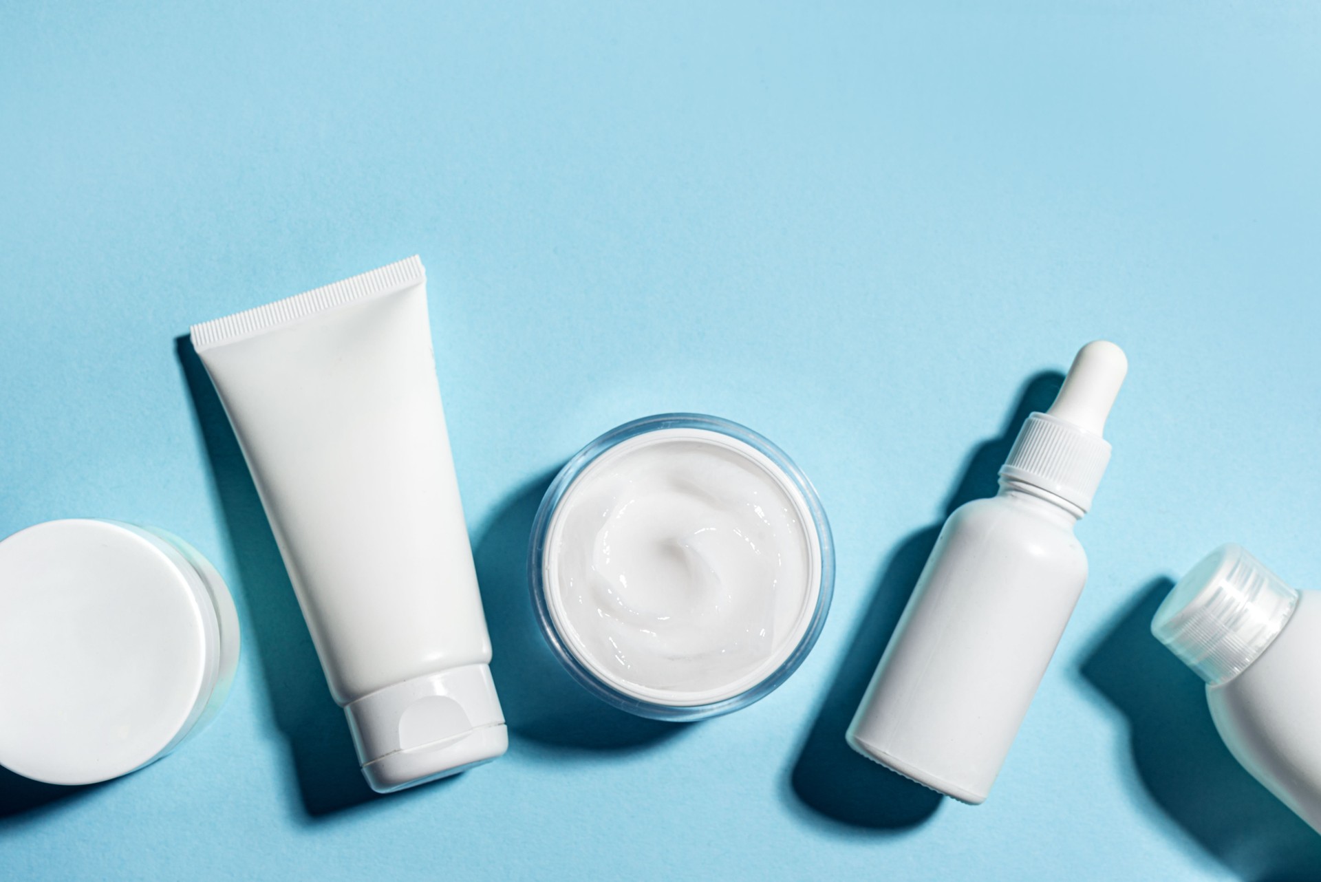 Various white cosmetic containers on blue background